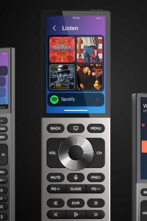 Close-up of a sleek touchscreen smart remote on the ‘Listen’ screen, showing album art tiles and a Spotify option; below the display are tactile controls including a metal navigation wheel, volume and channel keys, mute, menu, guide, DVR, and playback buttons.